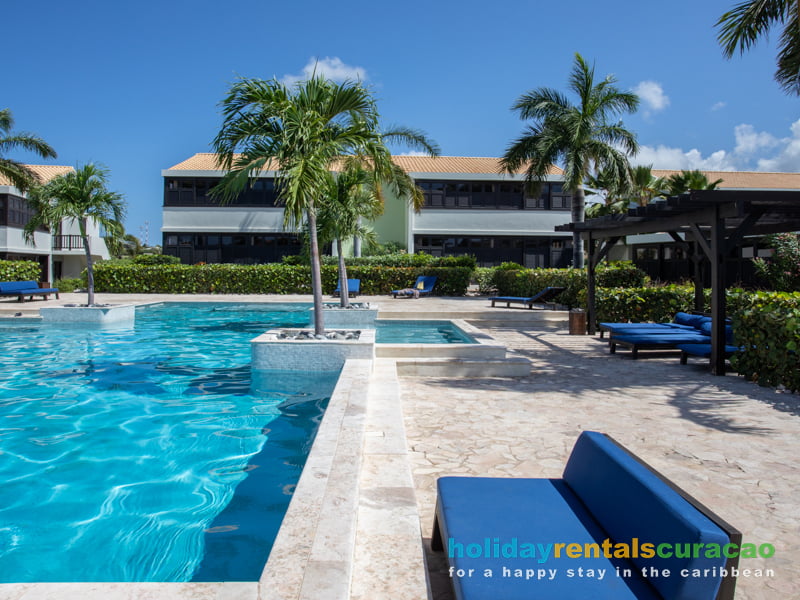 Tropischer Swimmingpool mit Liegestühlen und Lounge-Sofas Blue Bay Curacao
